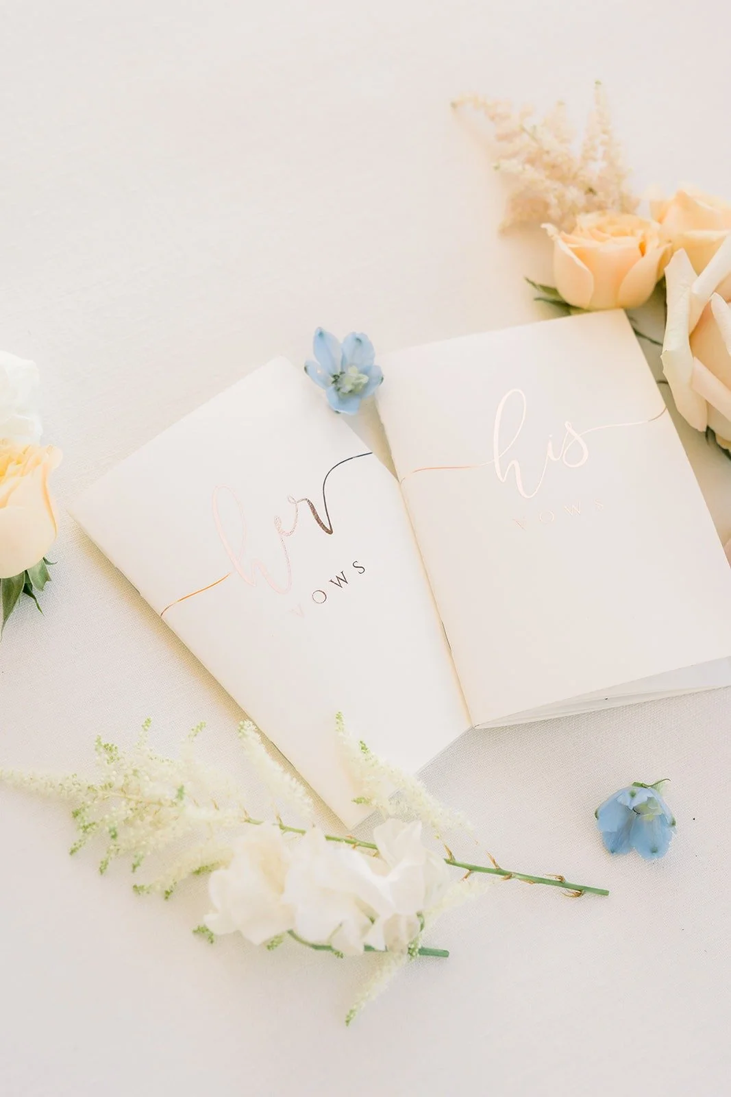 Vow books styled with white blooms and blue accents
