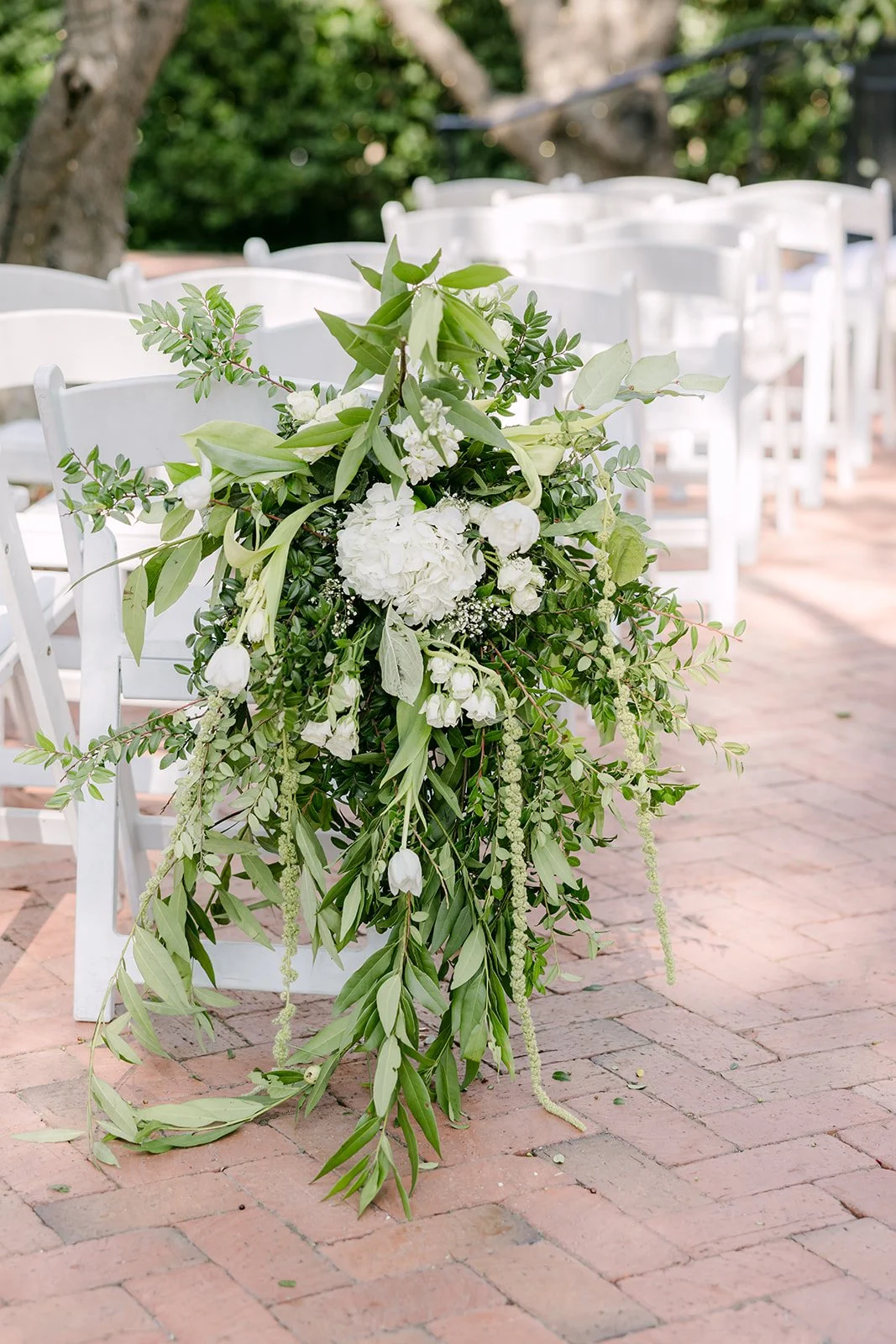 White hydrangea and trailing greenery on an aisle chair