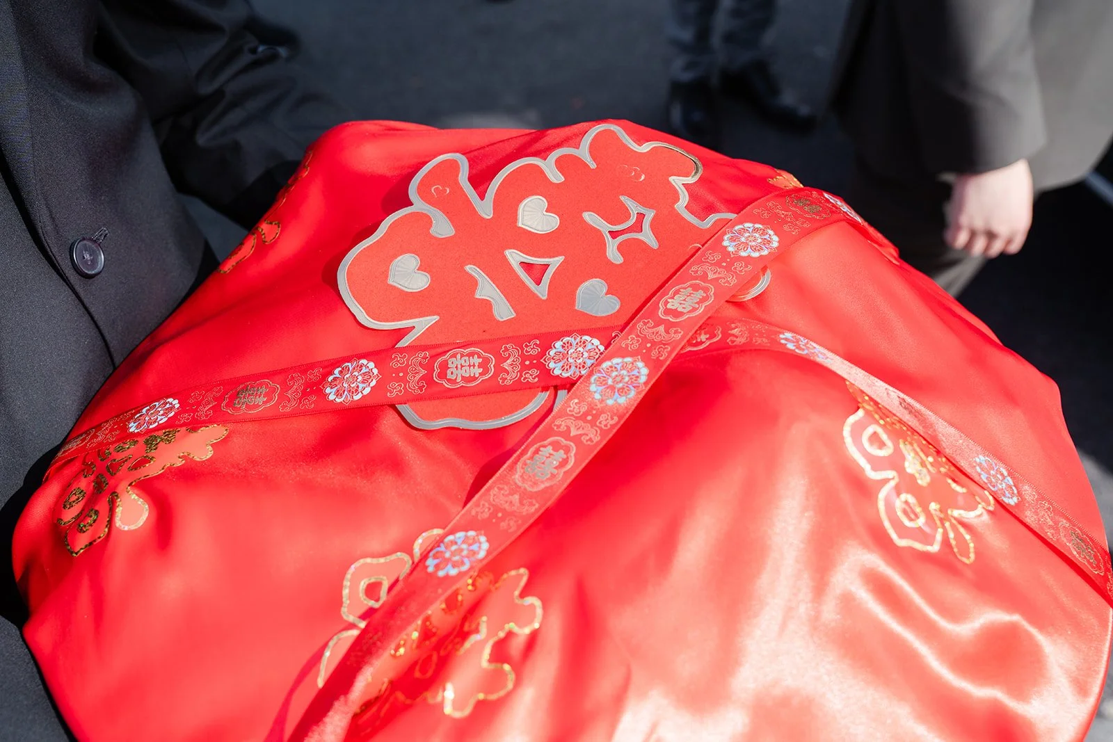 The groom lifting the red veil from the bride's embroidered qun kwa, photographed by One and Only Production.