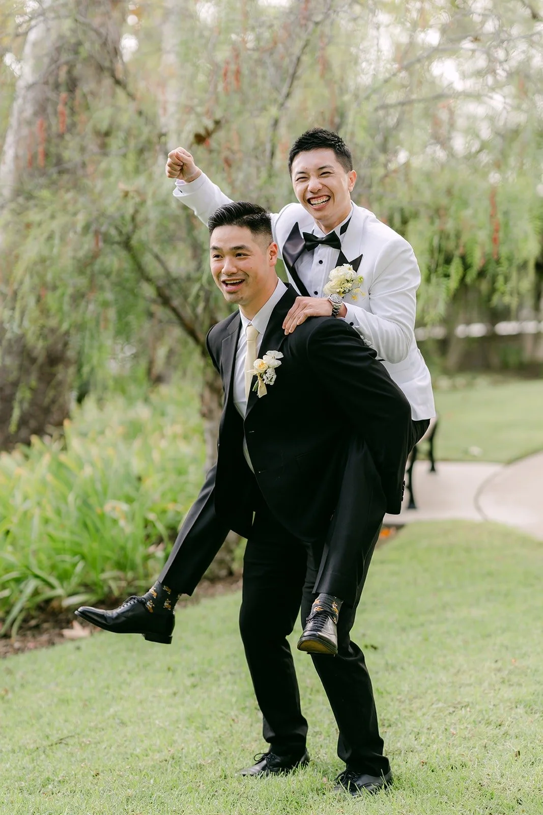 Ryan riding piggyback on a groomsman and laughing.
