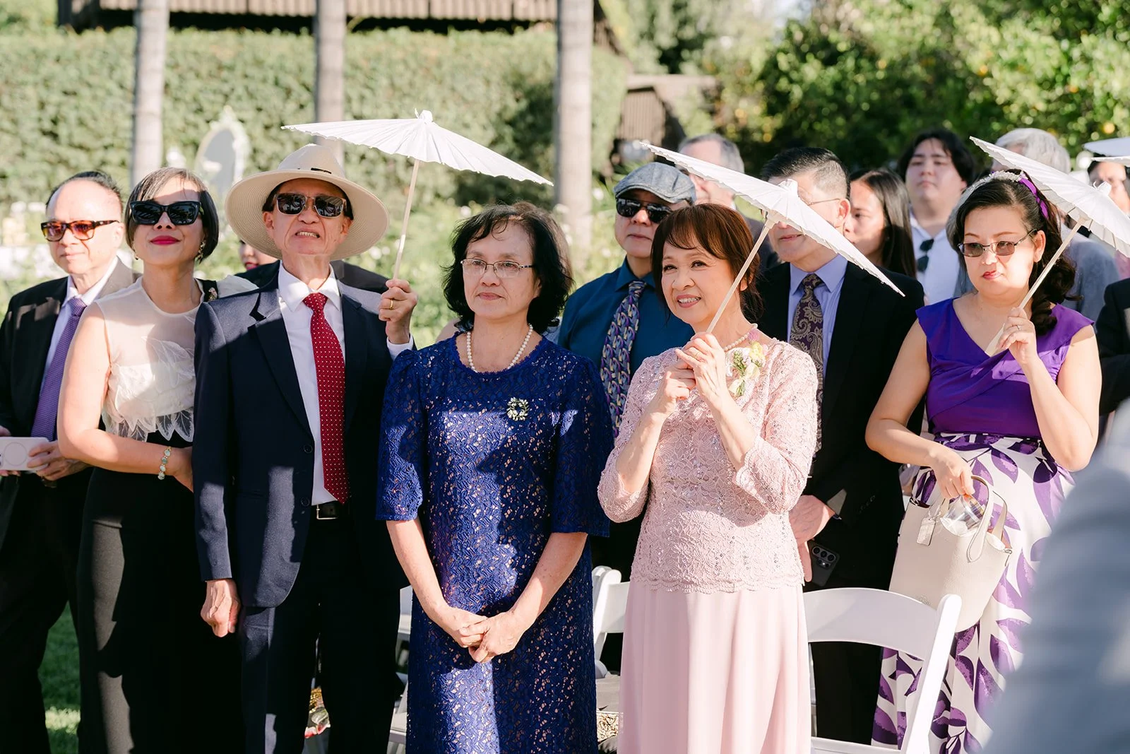 Guests holding white parasols during the ceremony.