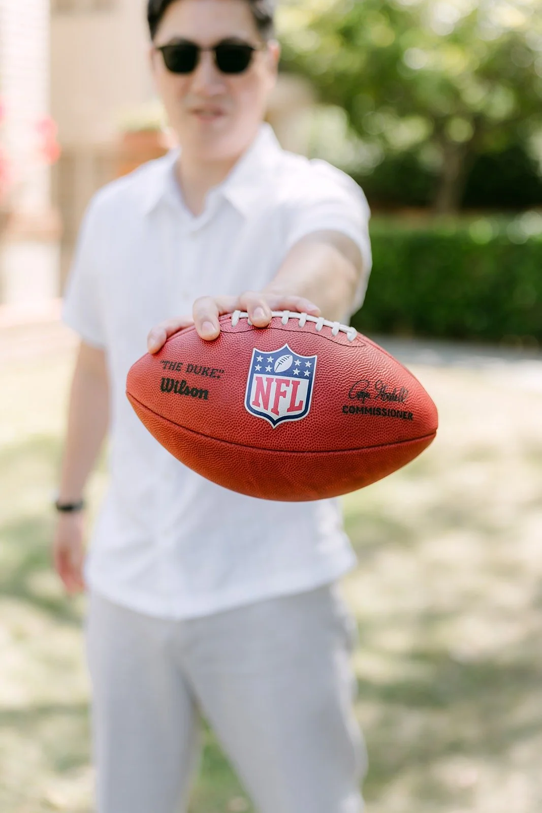 A groomsman holding a football out toward the camera