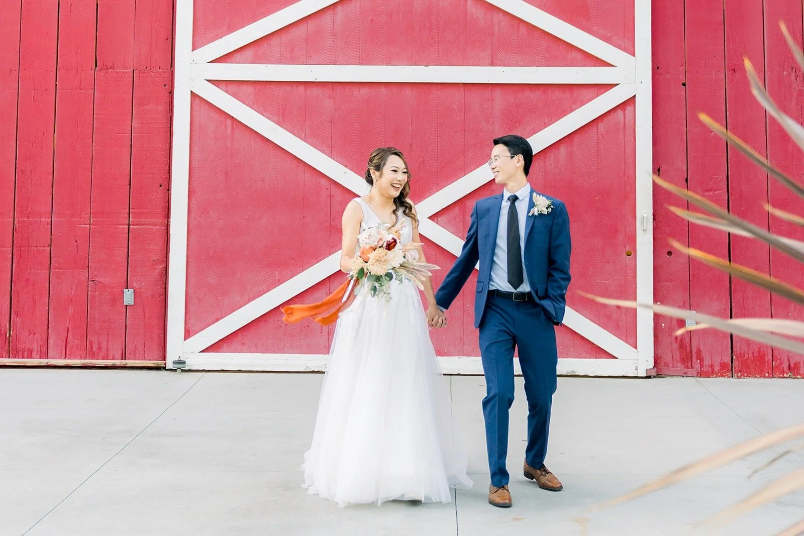 Ariel and Alex laughing in front of the red barn doors