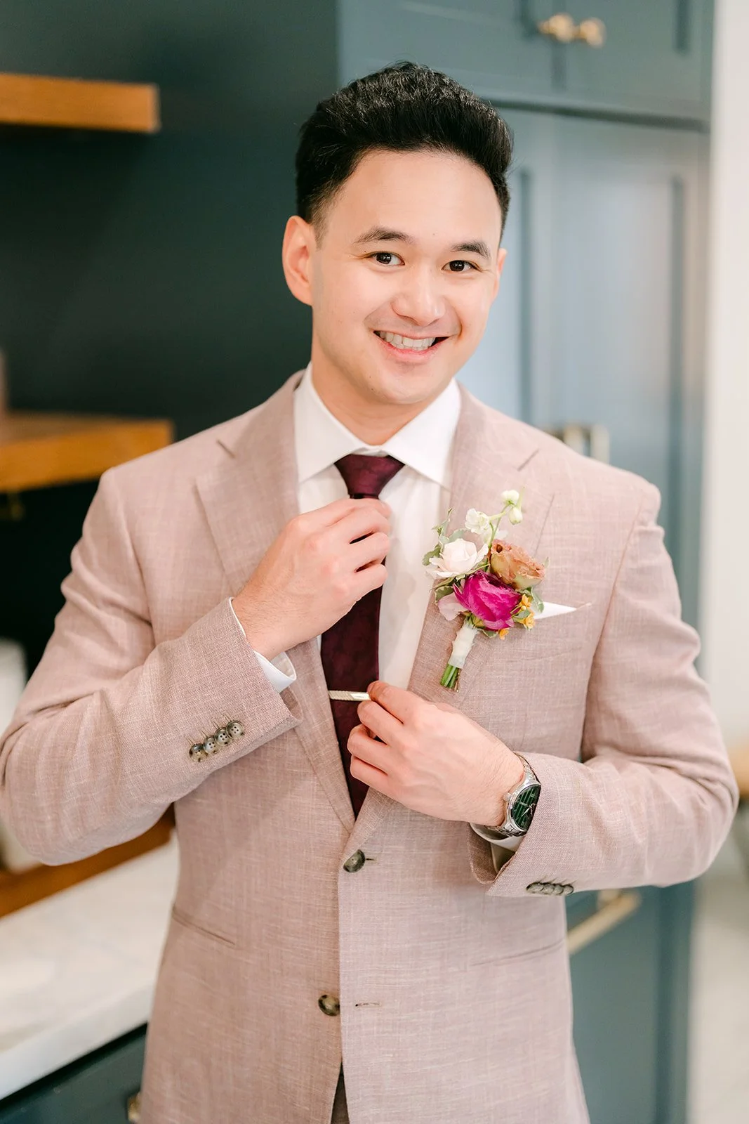 Michael smiling as he buttons his blush suit jacket.