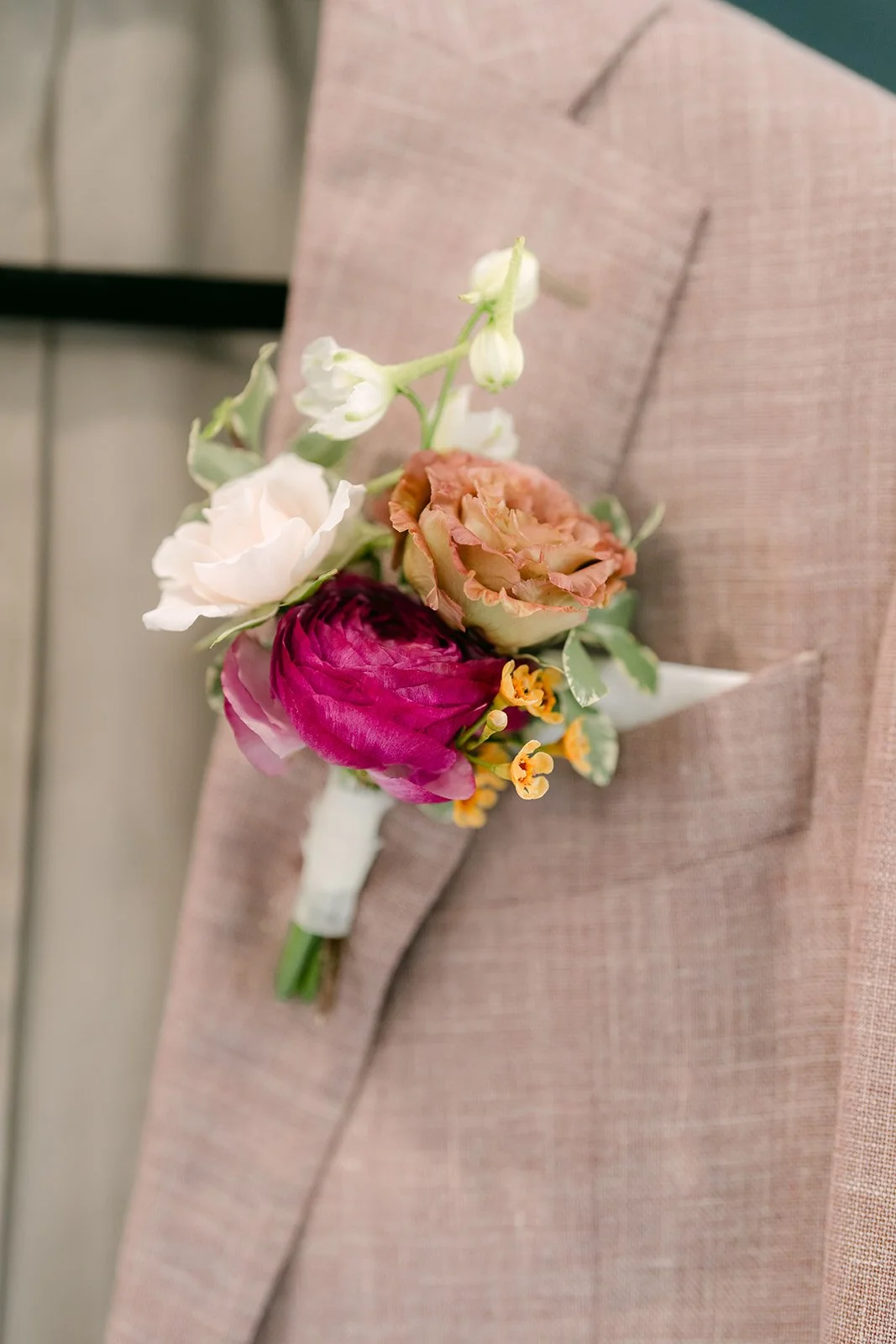 Close-up of Michael's boutonniere with a rose and a burgundy bloom.