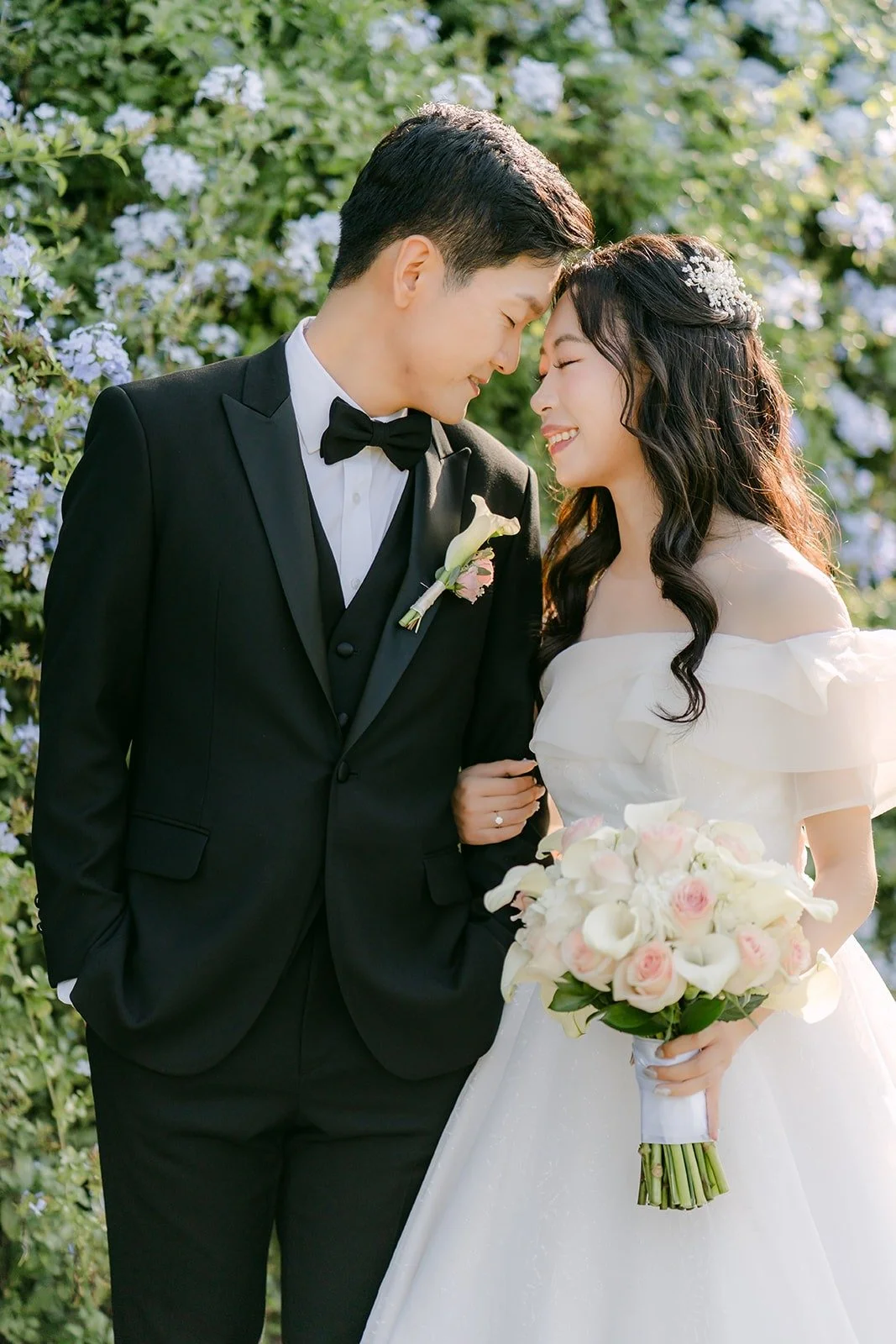 Jeannie and Eunsang forehead to forehead by the blue blossoms