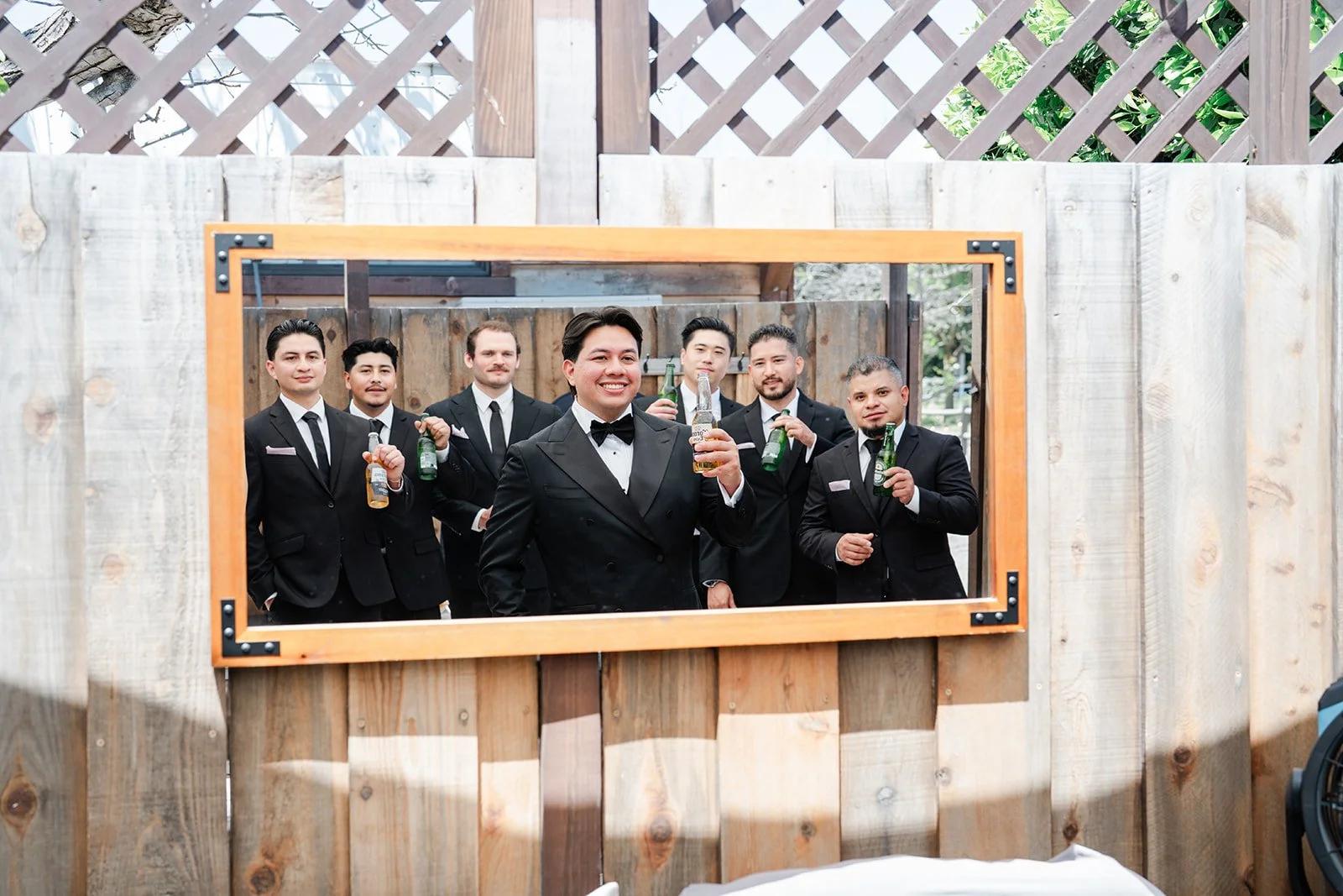 Groomsmen posing inside a wooden frame with drinks