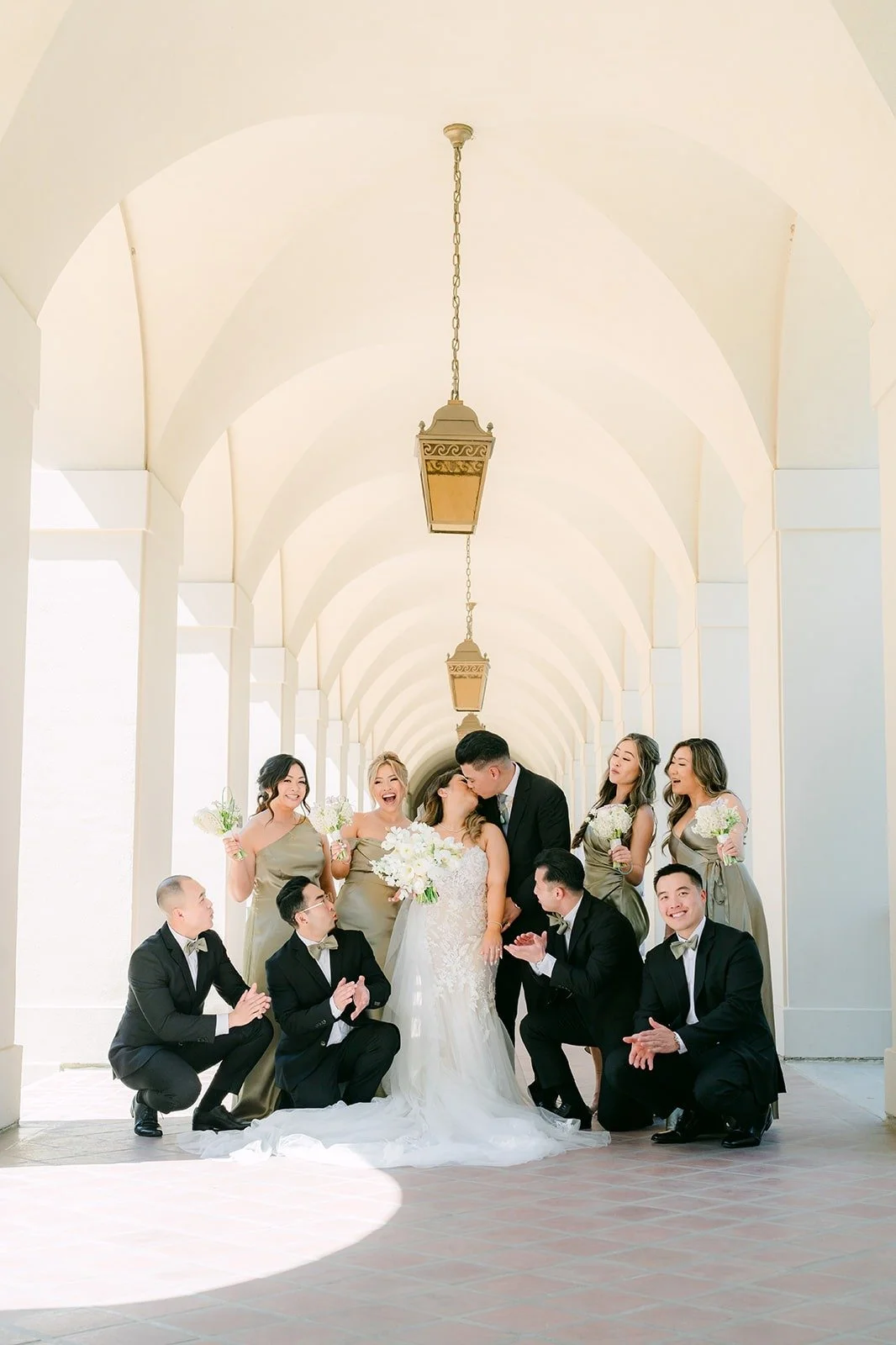 Wedding party cheering around Candice and Vincent in the colonnade