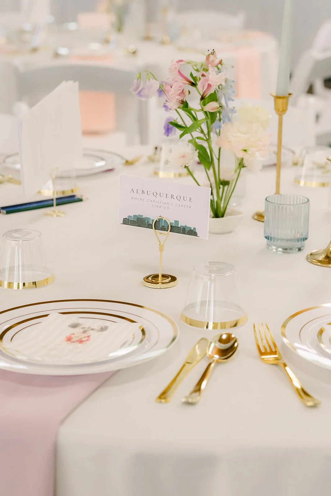 A guest place setting with a bud vase and gold-rimmed plate.
