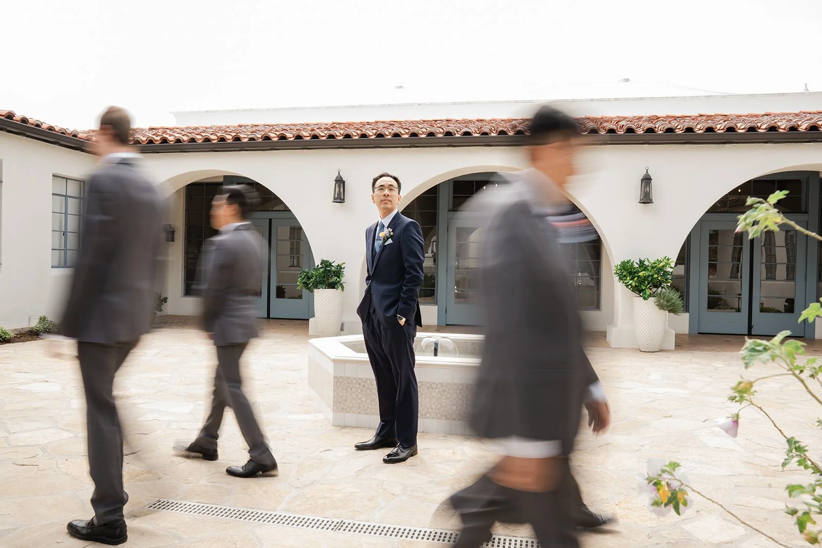 Groomsmen walking past Lawrence in the courtyard