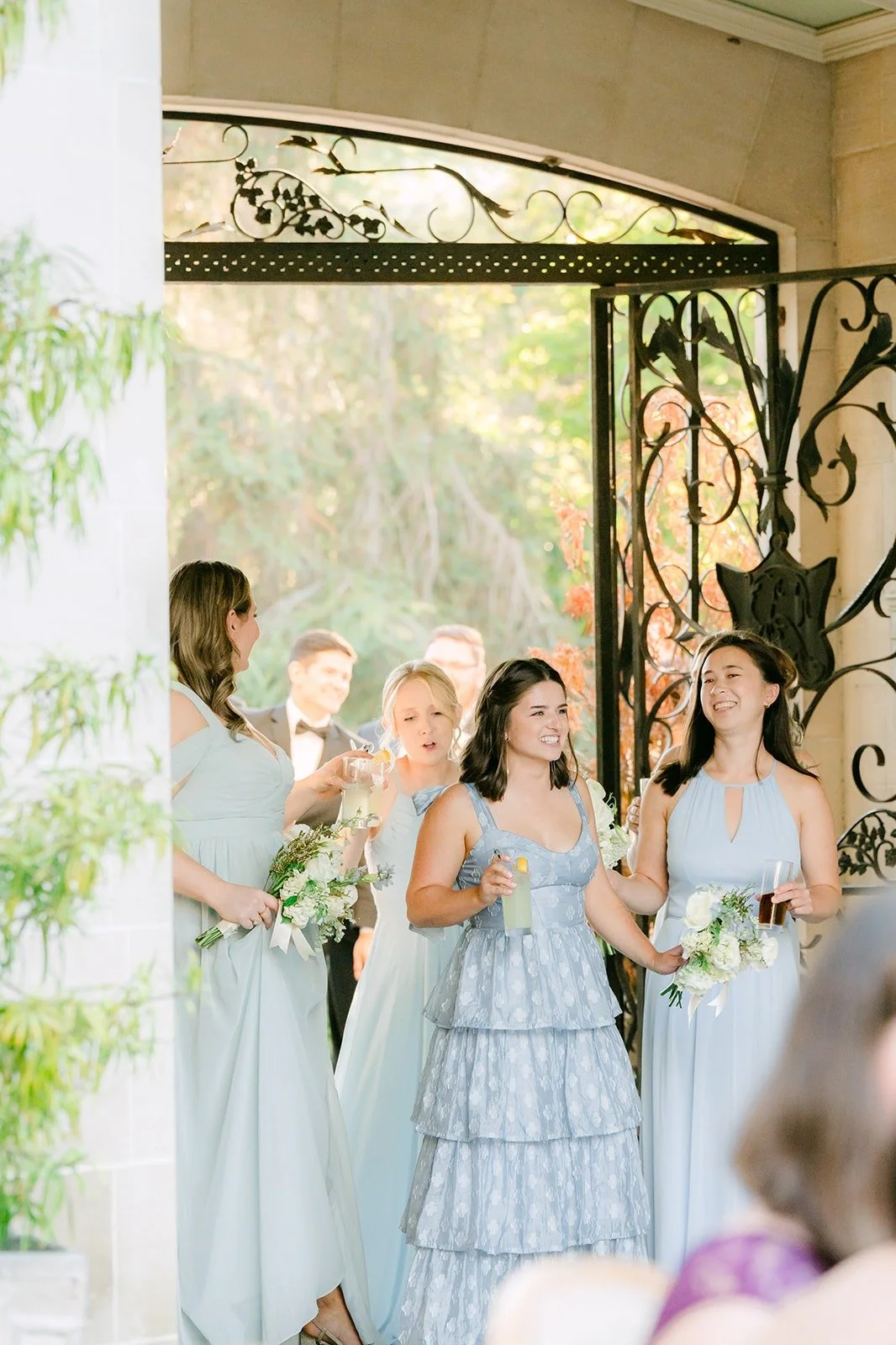 Bridesmaids making their entrance through the wrought iron gate