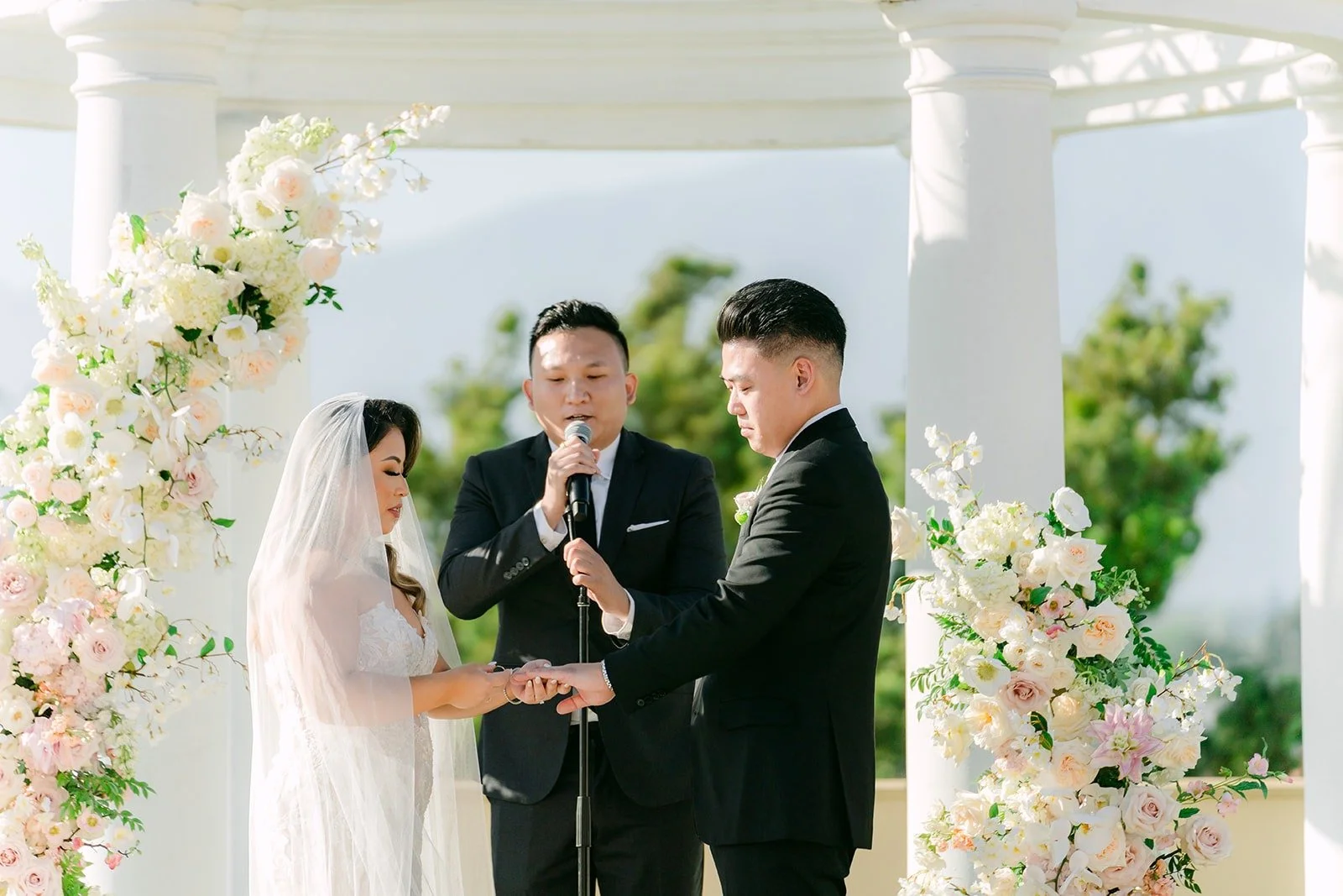 Candice and Vincent exchanging rings at the floral altar