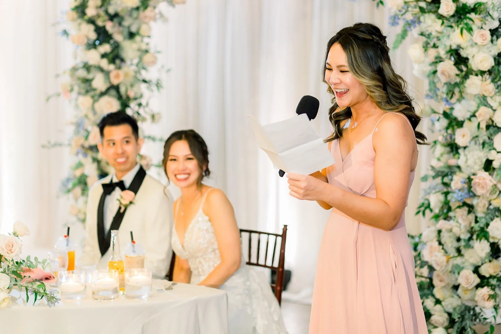 A bridesmaid giving a speech beside the sweetheart table