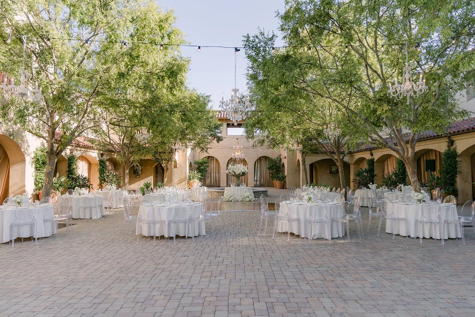 Round reception tables set beneath the courtyard trees