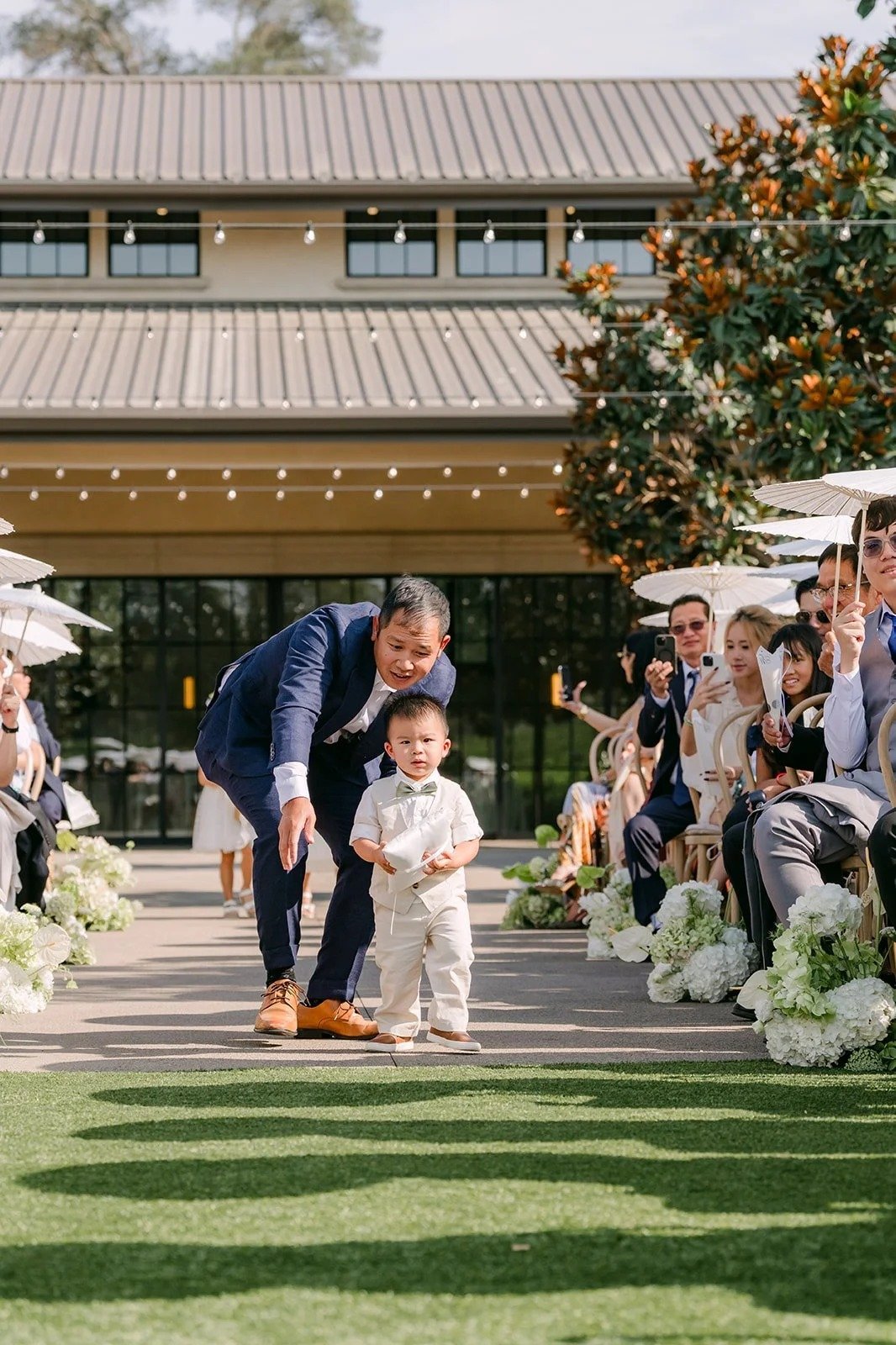 Ring bearer pausing down the aisle as guests smile