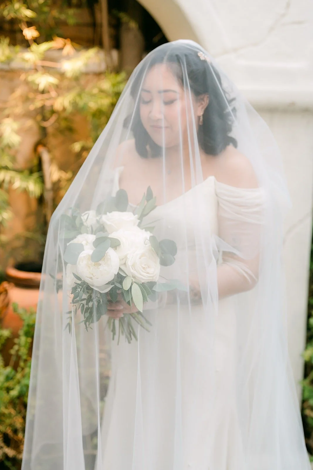 Vivian under her veil with her white rose bouquet