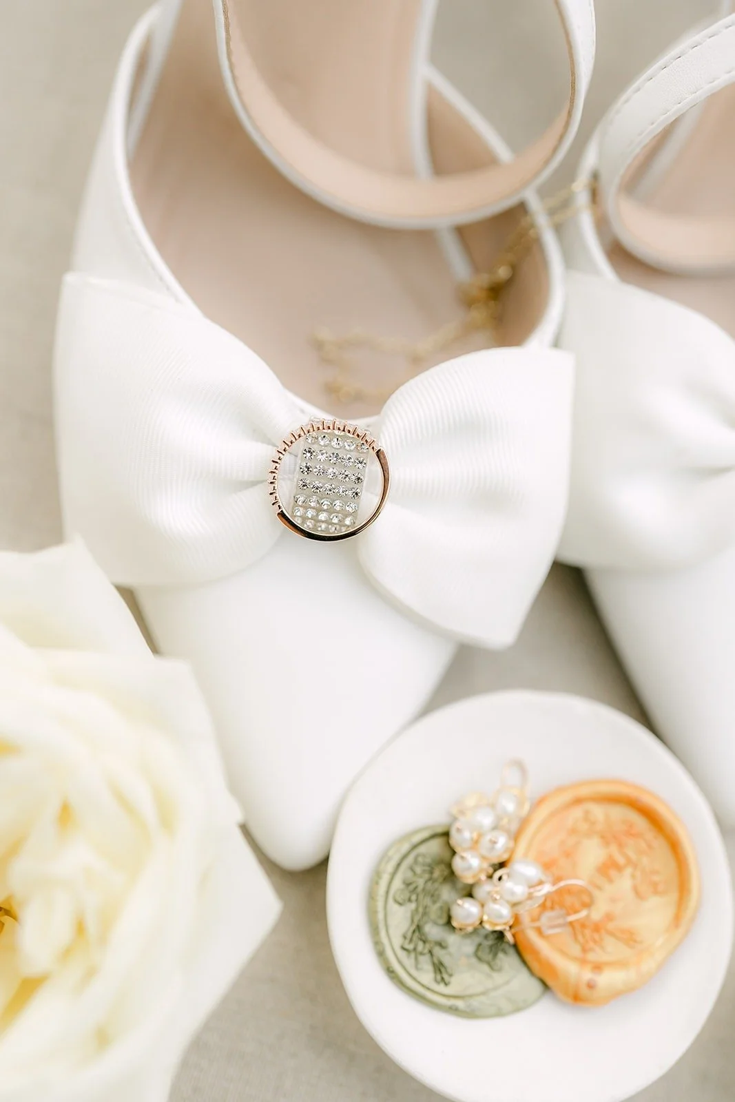 Mariana's white bow heels with a wax seal and rings