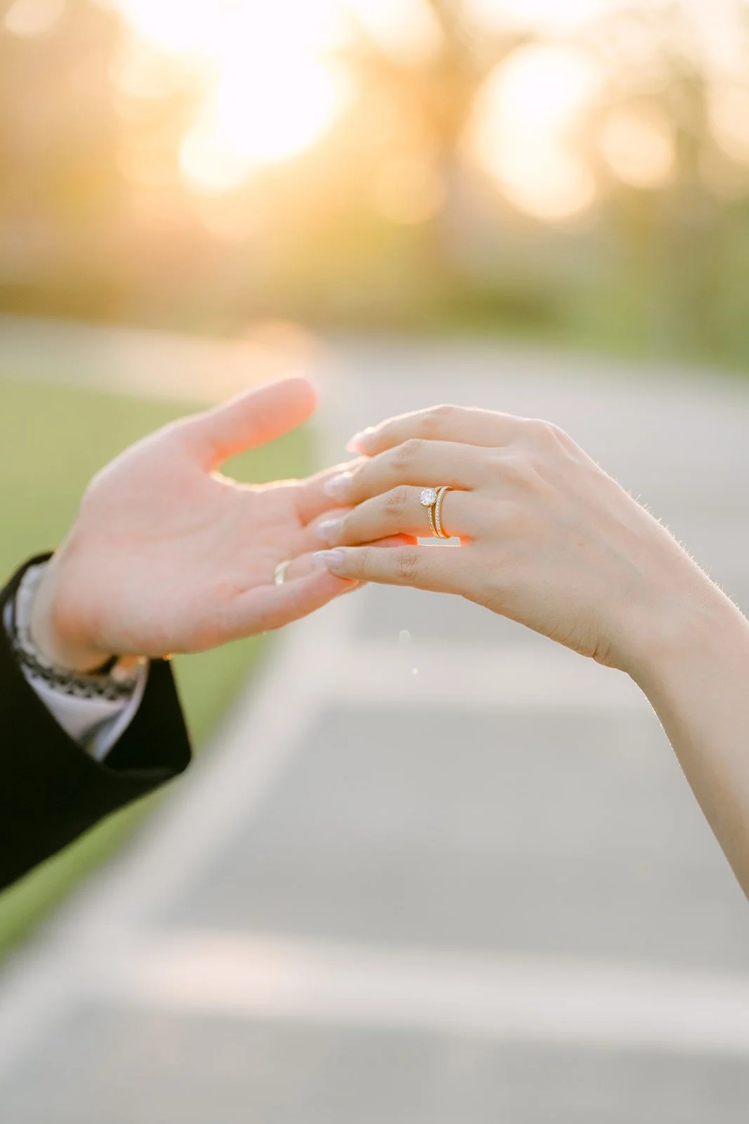 Stephanie and Kevin's hands and wedding rings against the setting sun
