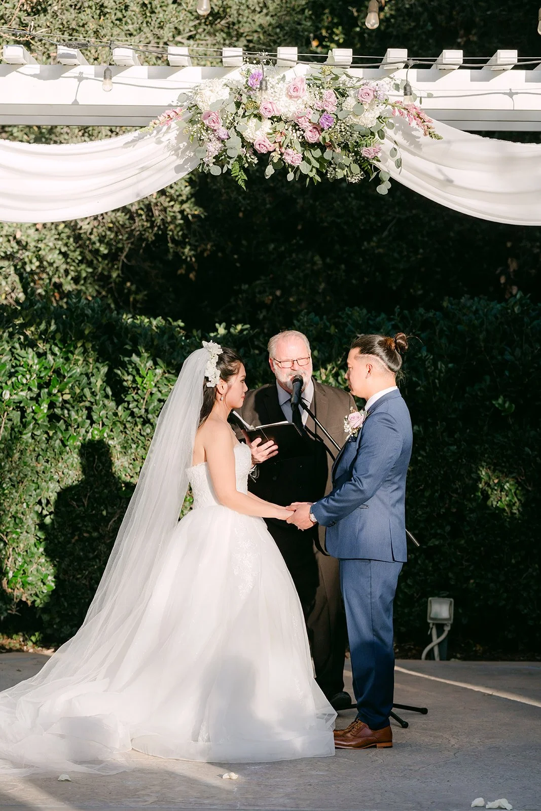 Kate and Michael with their officiant under the pergola.