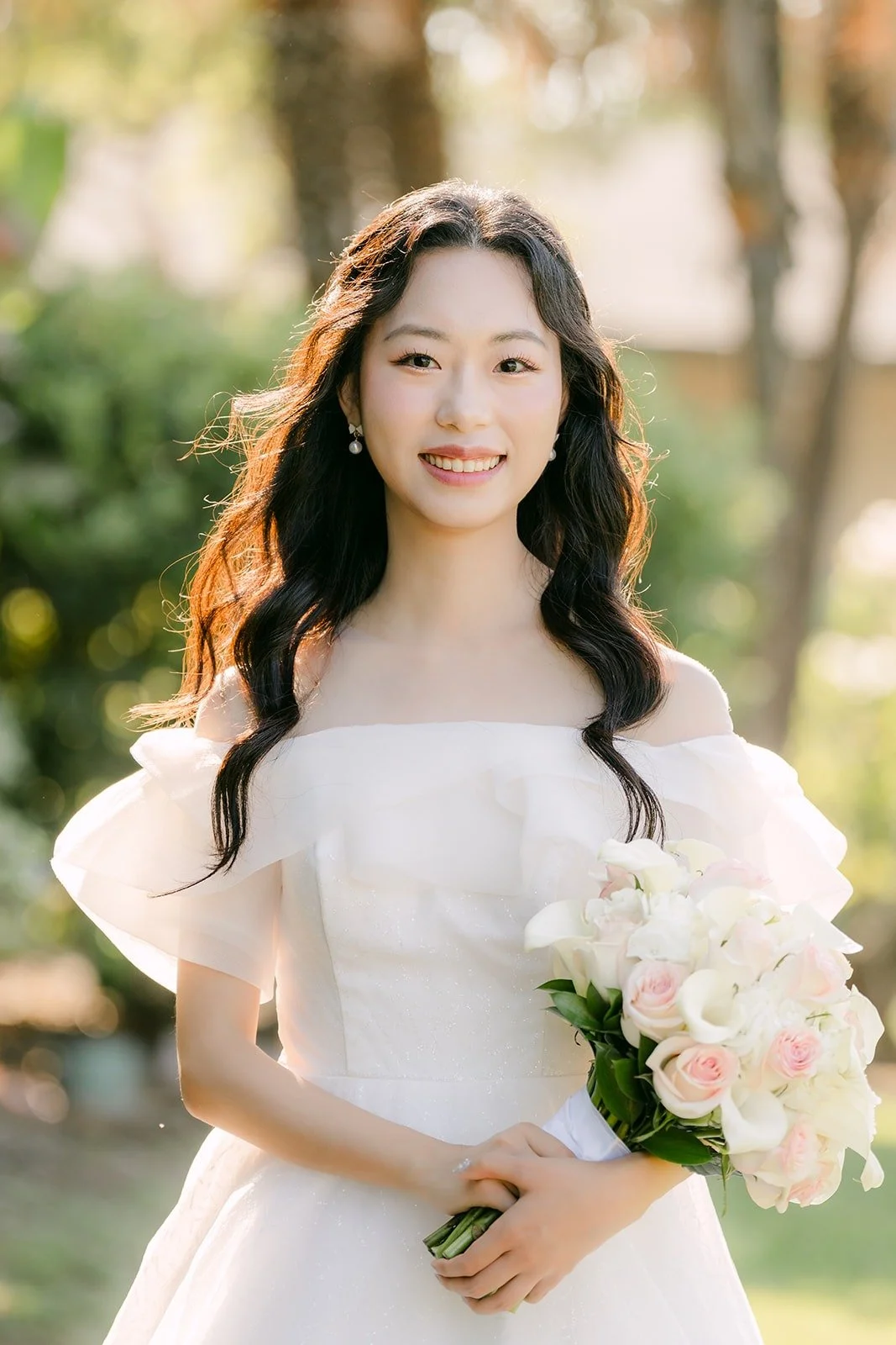 Jeannie smiling softly with her bouquet in the garden light