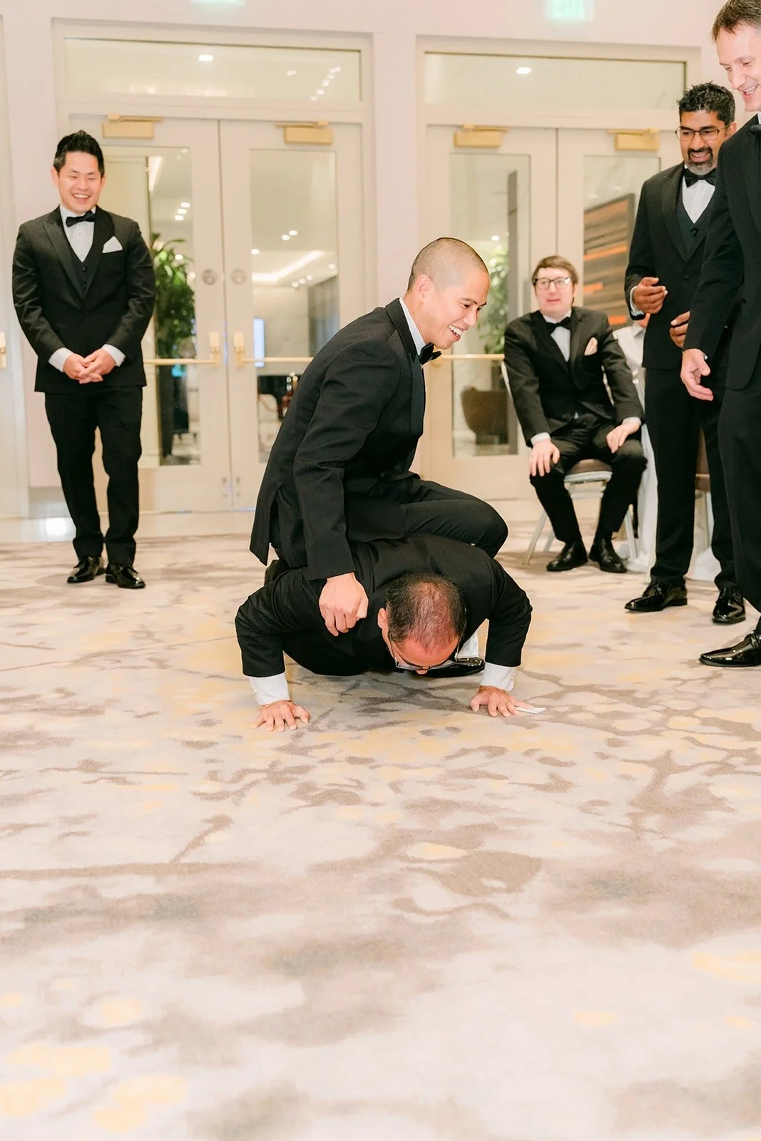 Groomsmen taking turns with push ups on the carpet as part of the door games