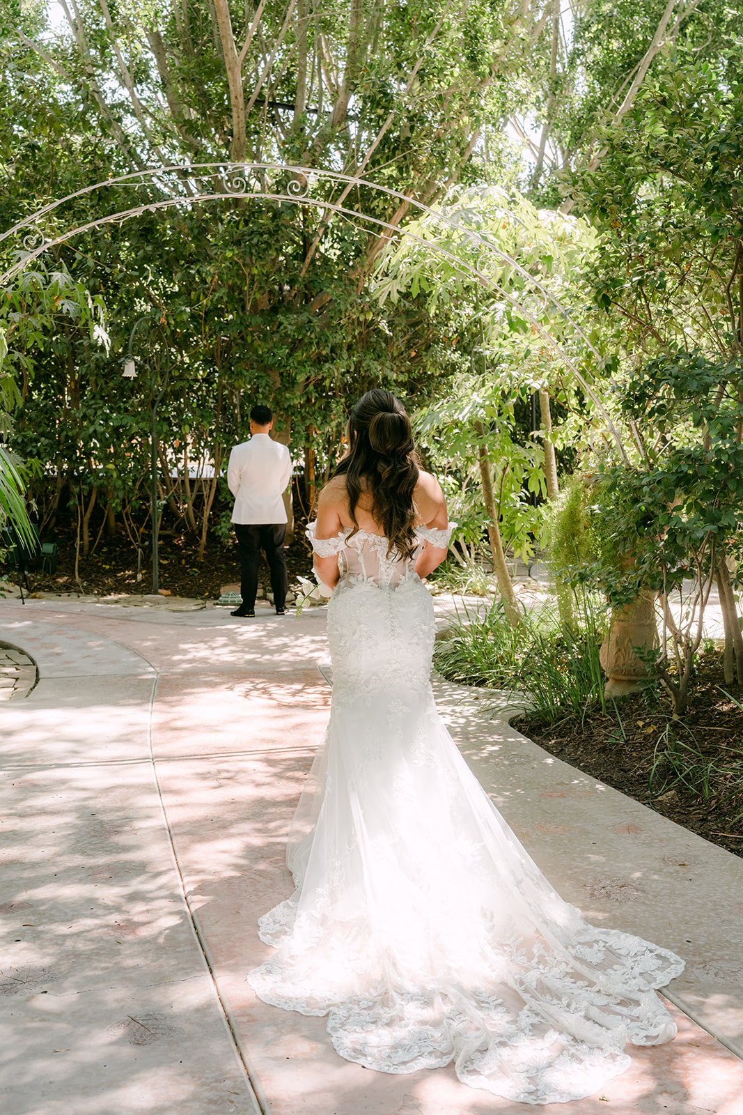 Nicole walking under the trees toward Caryl for their first look.