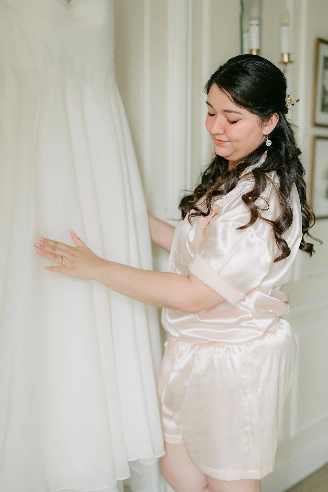 Saira reaching for her wedding dress in a satin robe