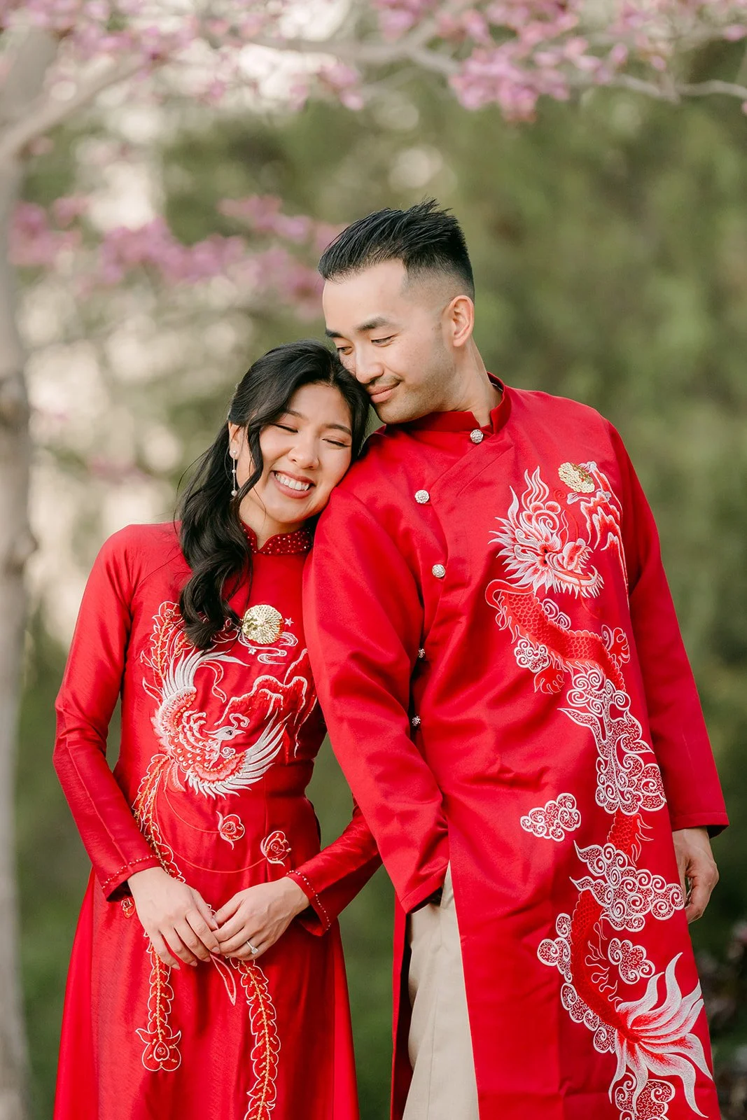 Close portrait of Kim and Vincent in red ao dai, cheek to cheek.
