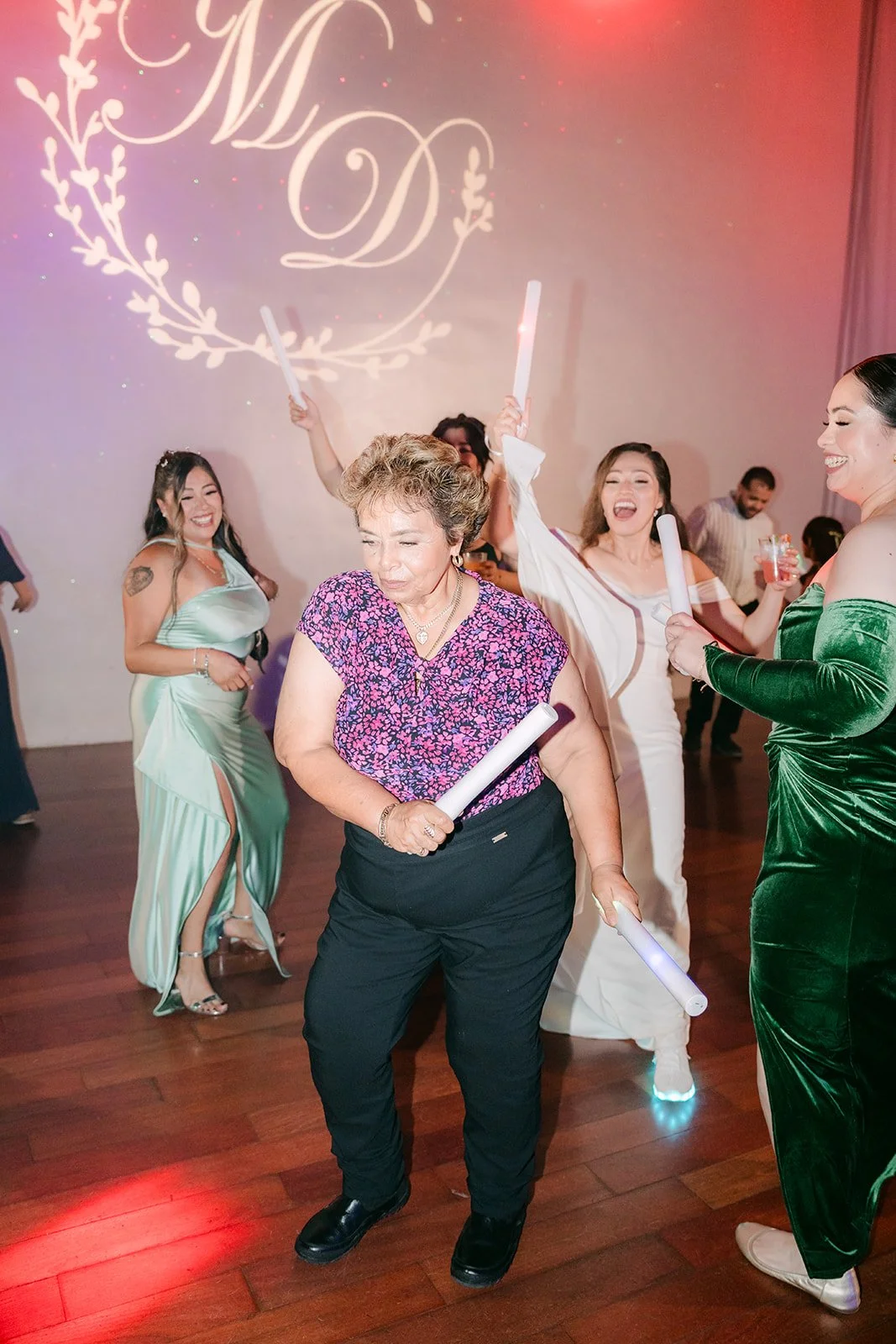 Guests dancing under pink lights with glow sticks