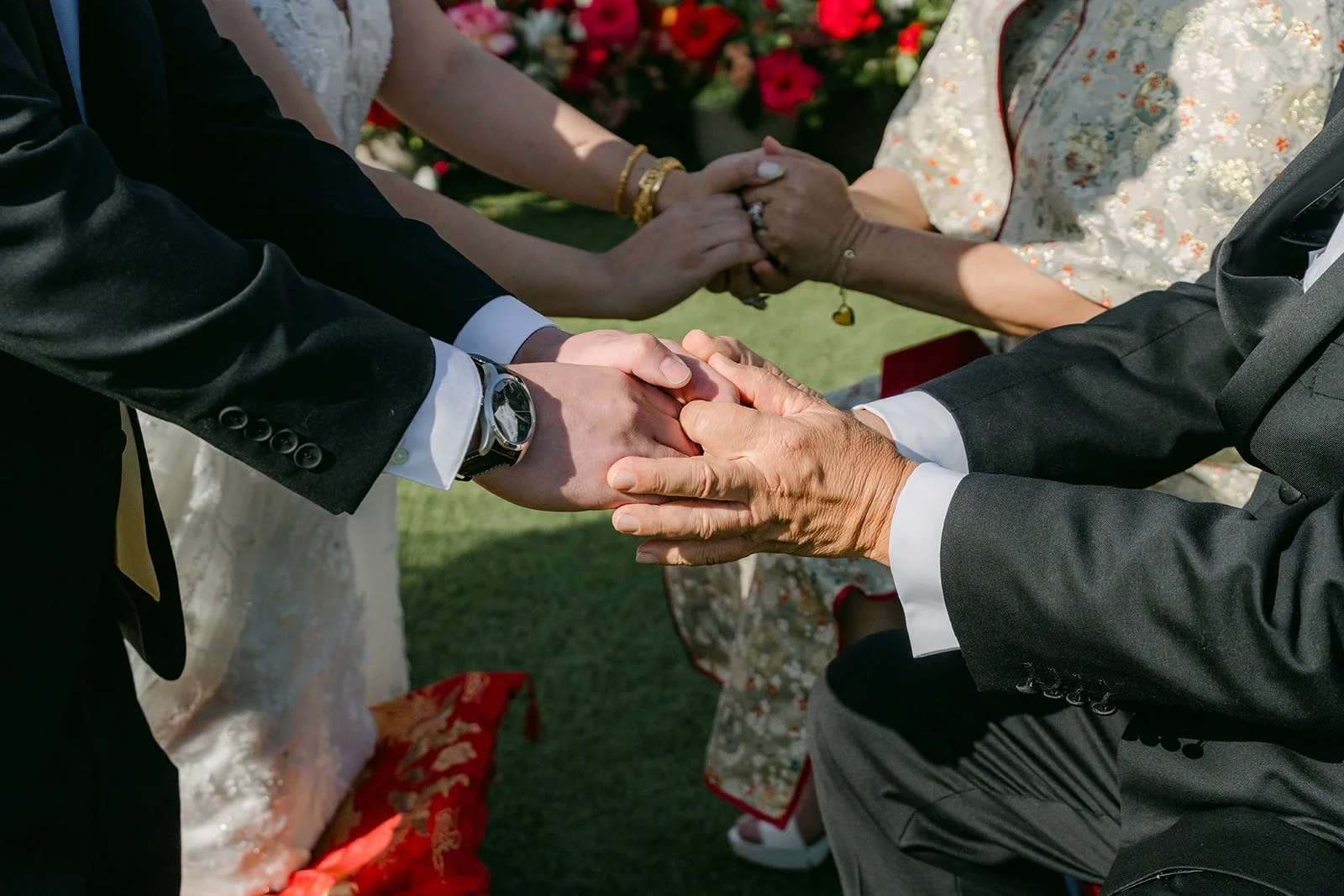 Joanne and Zach holding hands with a family member during the tea ceremony