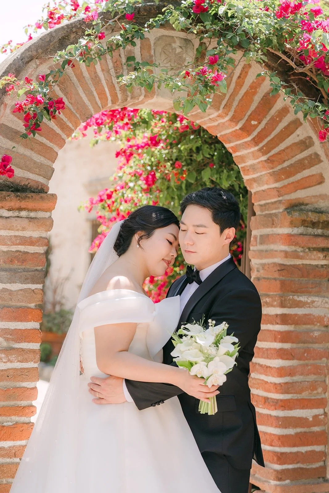 Chorok and Min Soo close together under the bougainvillea arch