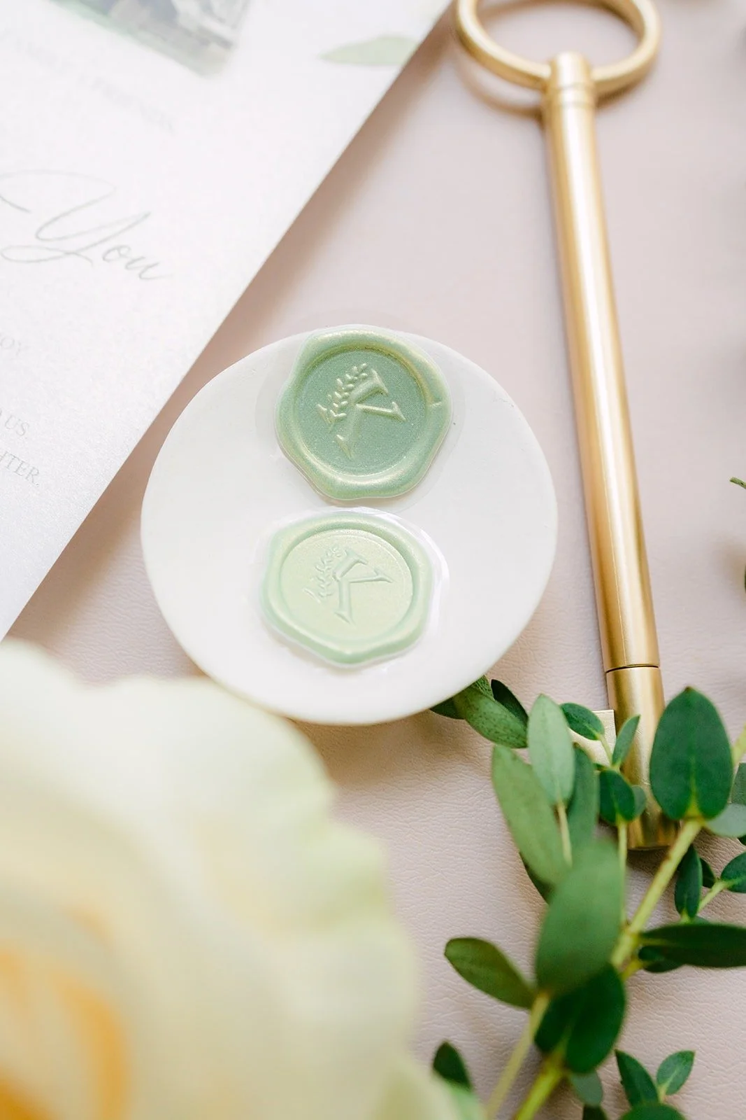 Sage green wax seals on a small dish beside a gold key