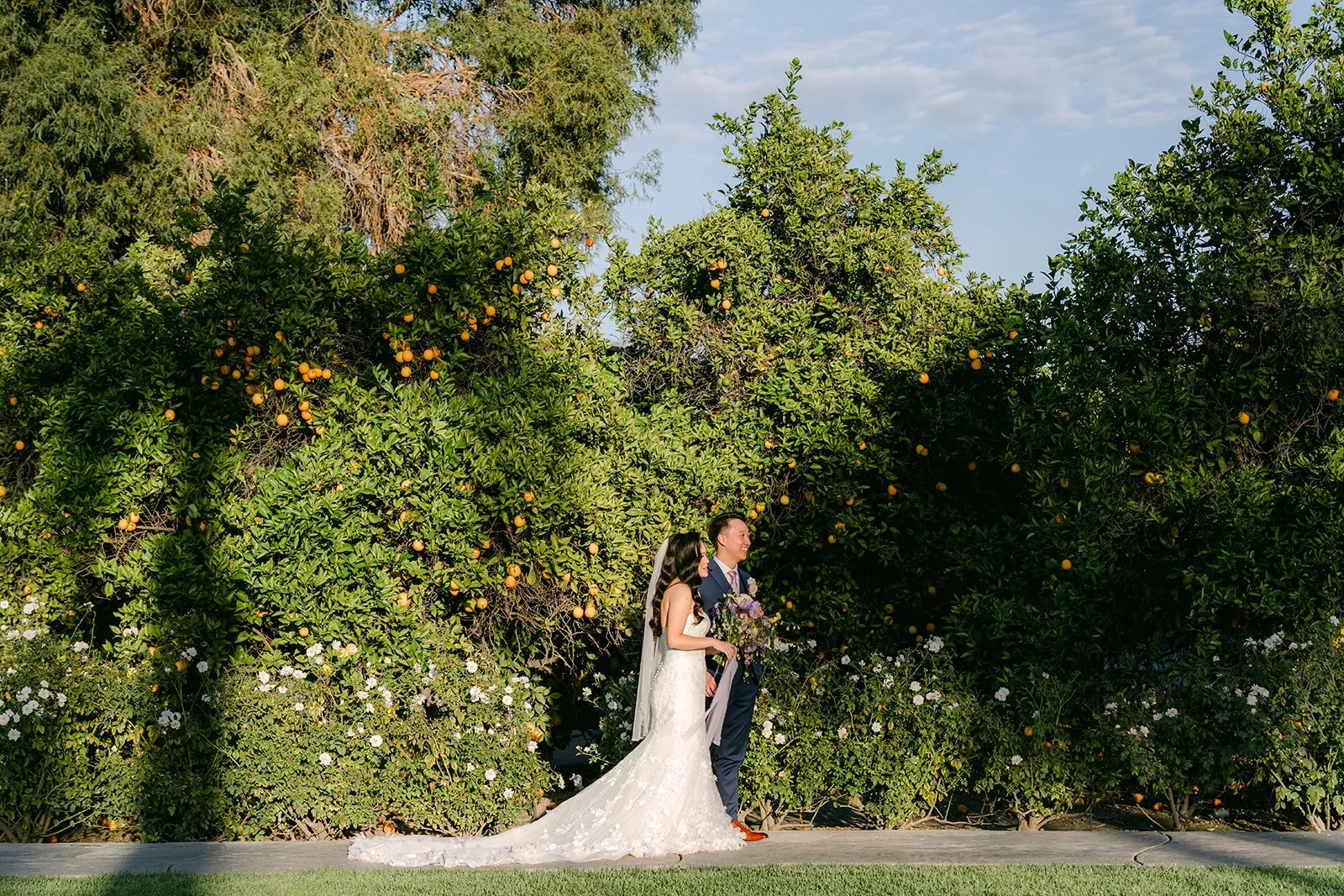 Vannie and Elijah in front of tall hedges in golden light.