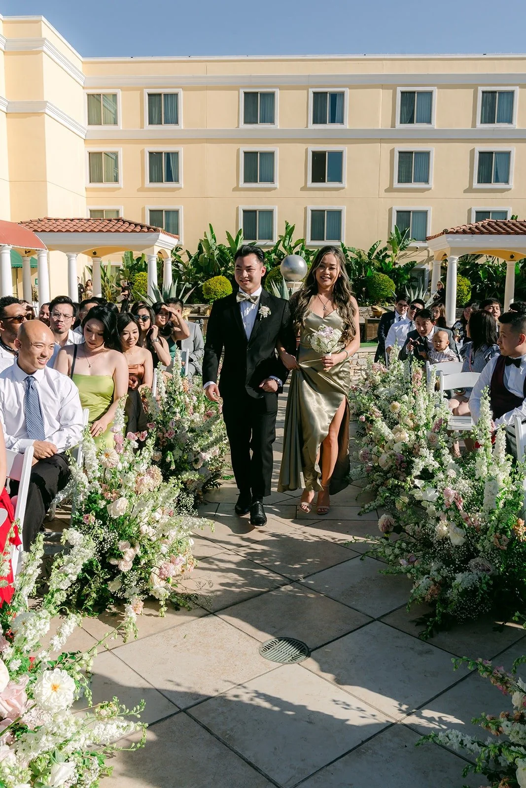 The wedding party walking in between floral aisle arrangements
