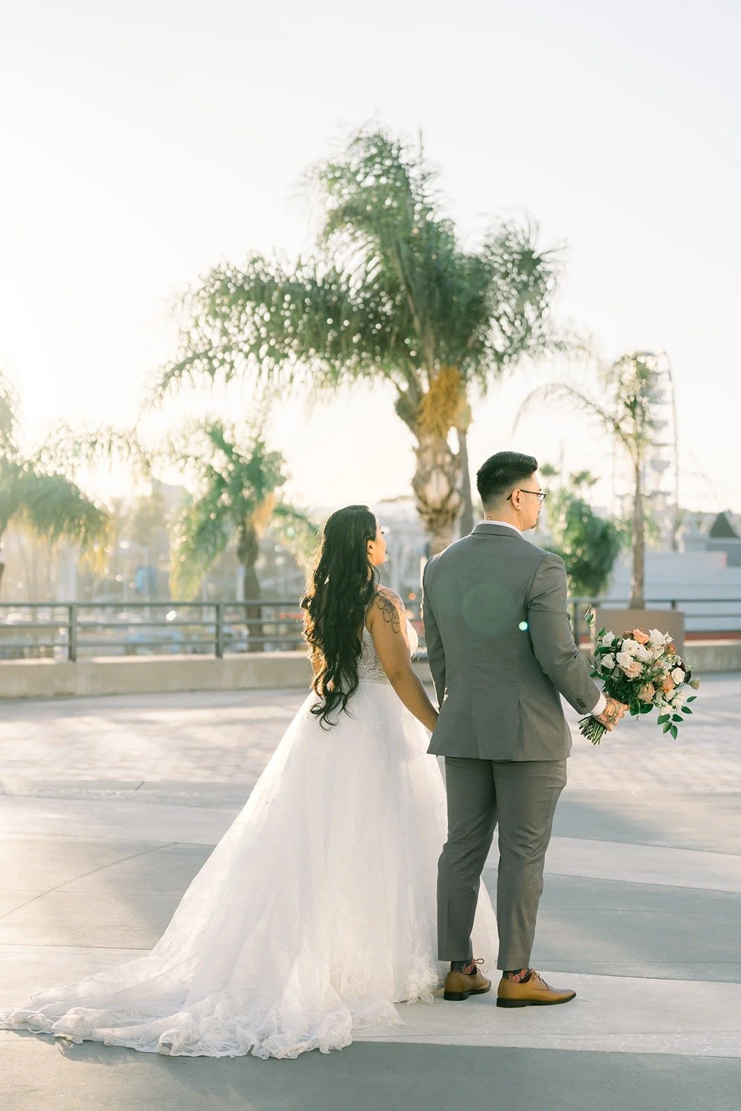 Betsy and Mikey walk among palm trees at golden hour