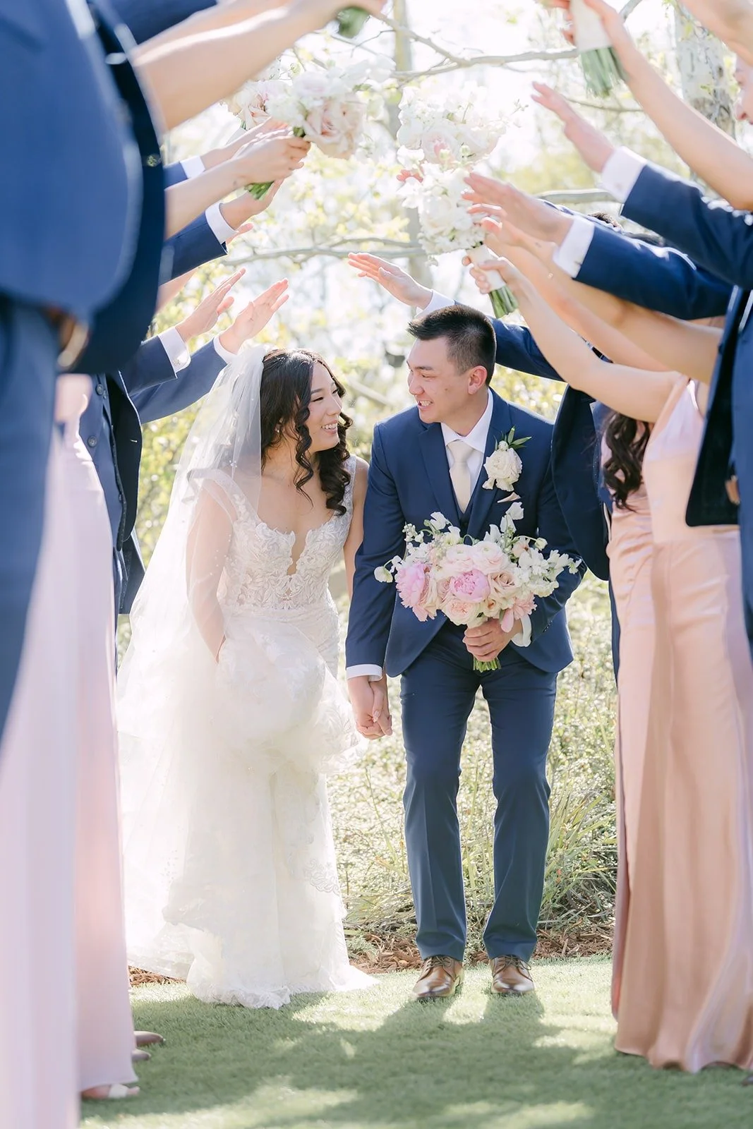 Kelli and Alex walking through a tunnel of bridesmaids' raised arms