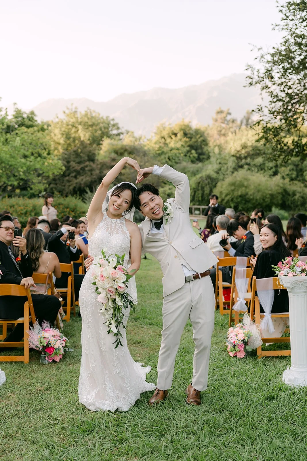 Elaine and Wen cheering with their arms up at the end of the aisle.