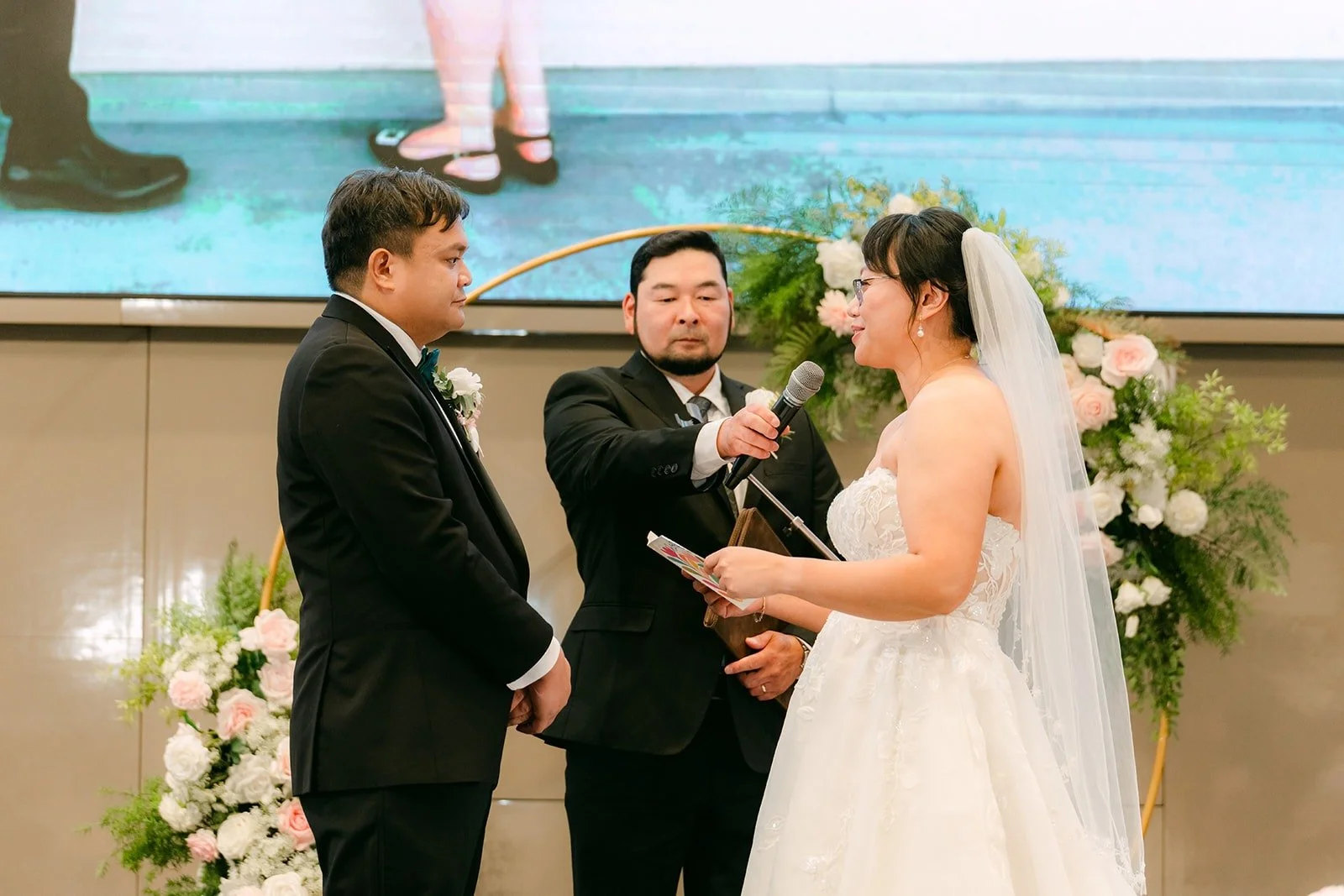 Stella and James holding hands in front of the officiant during the ceremony