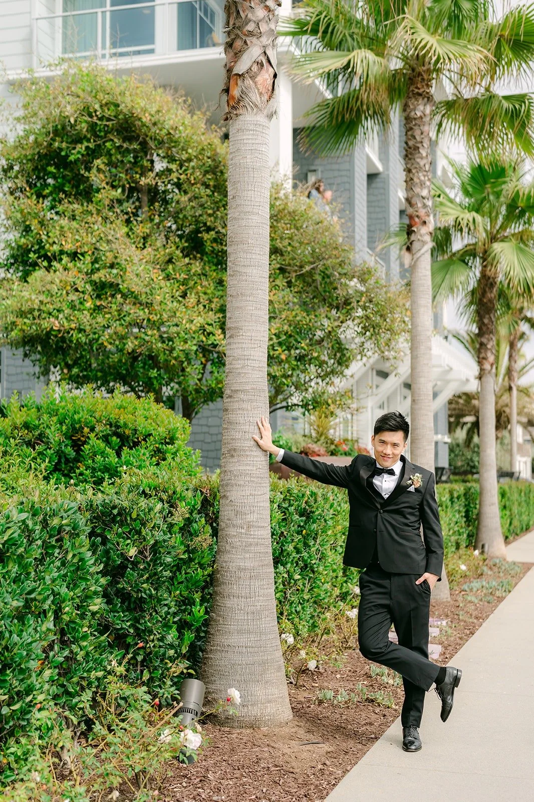 Eli leaning against a palm tree on a garden path at Seabird Resort