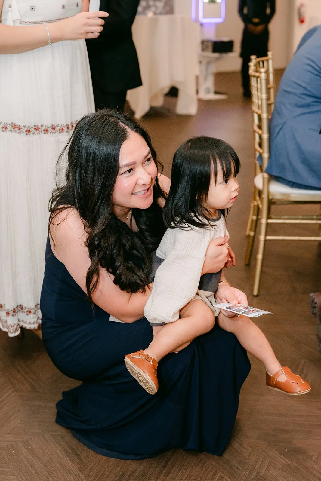 A bridesmaid laughing with a little guest during the shoe game.