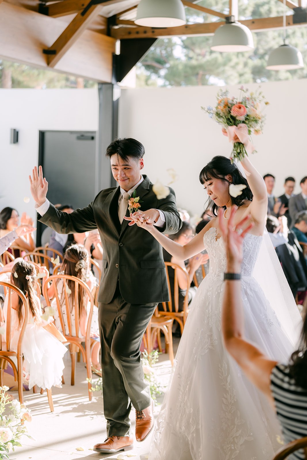 Newlyweds cheering as they walk back up the aisle at The Colony House