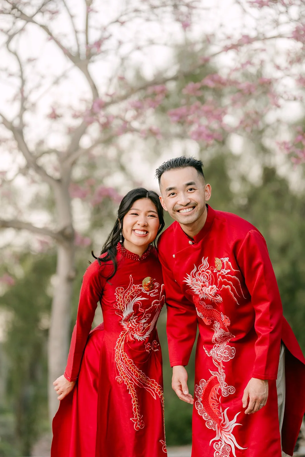 Kim and Vincent laughing together under the pink blossoms.