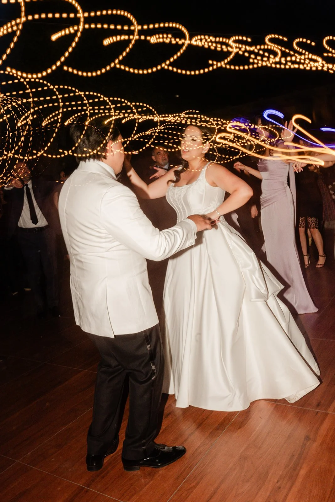 Couple dancing with string light trails behind them