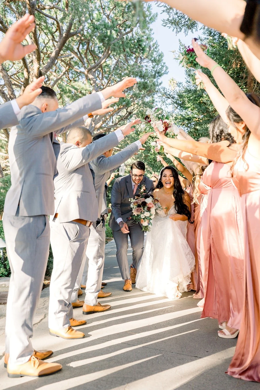 The wedding party cheers with raised arms for Betsy and Mikey