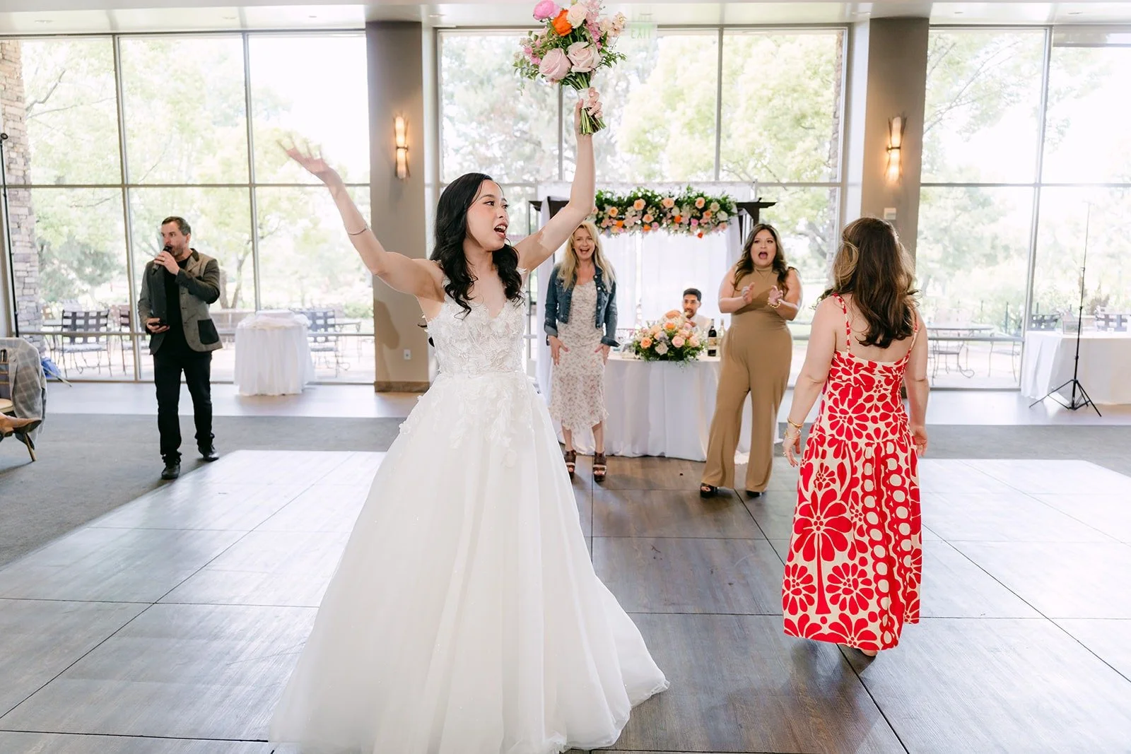 Natalie tossing her bouquet over her shoulder in the ballroom
