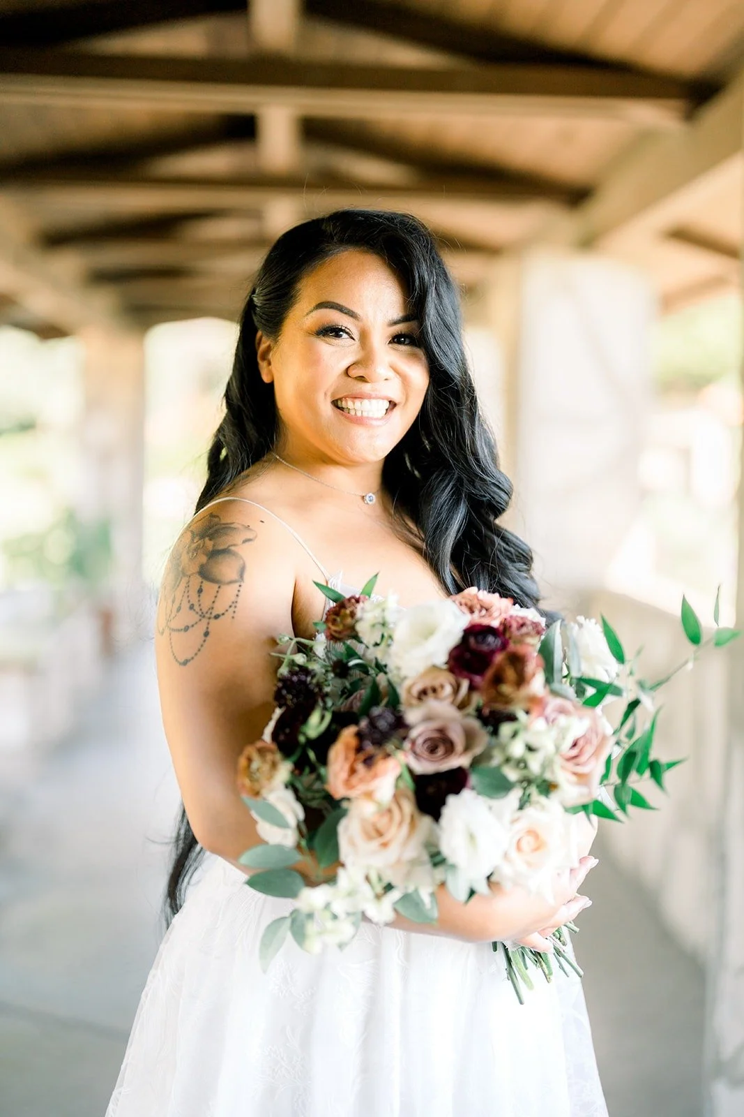 Betsy smiles over her burgundy and blush bouquet