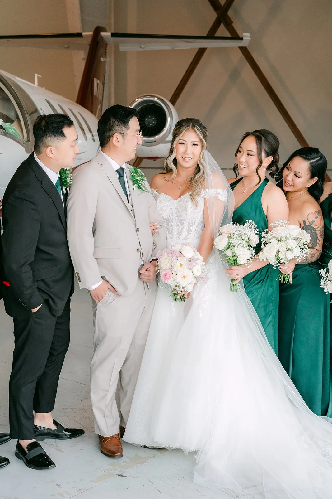 Bride and groom with friends beside the jet in the hangar