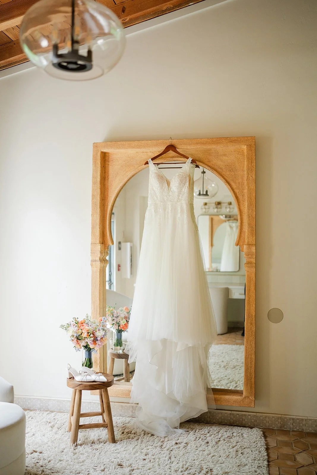 Wedding gown hanging on an arched wooden mirror in the bridal suite at Grand Gimeno