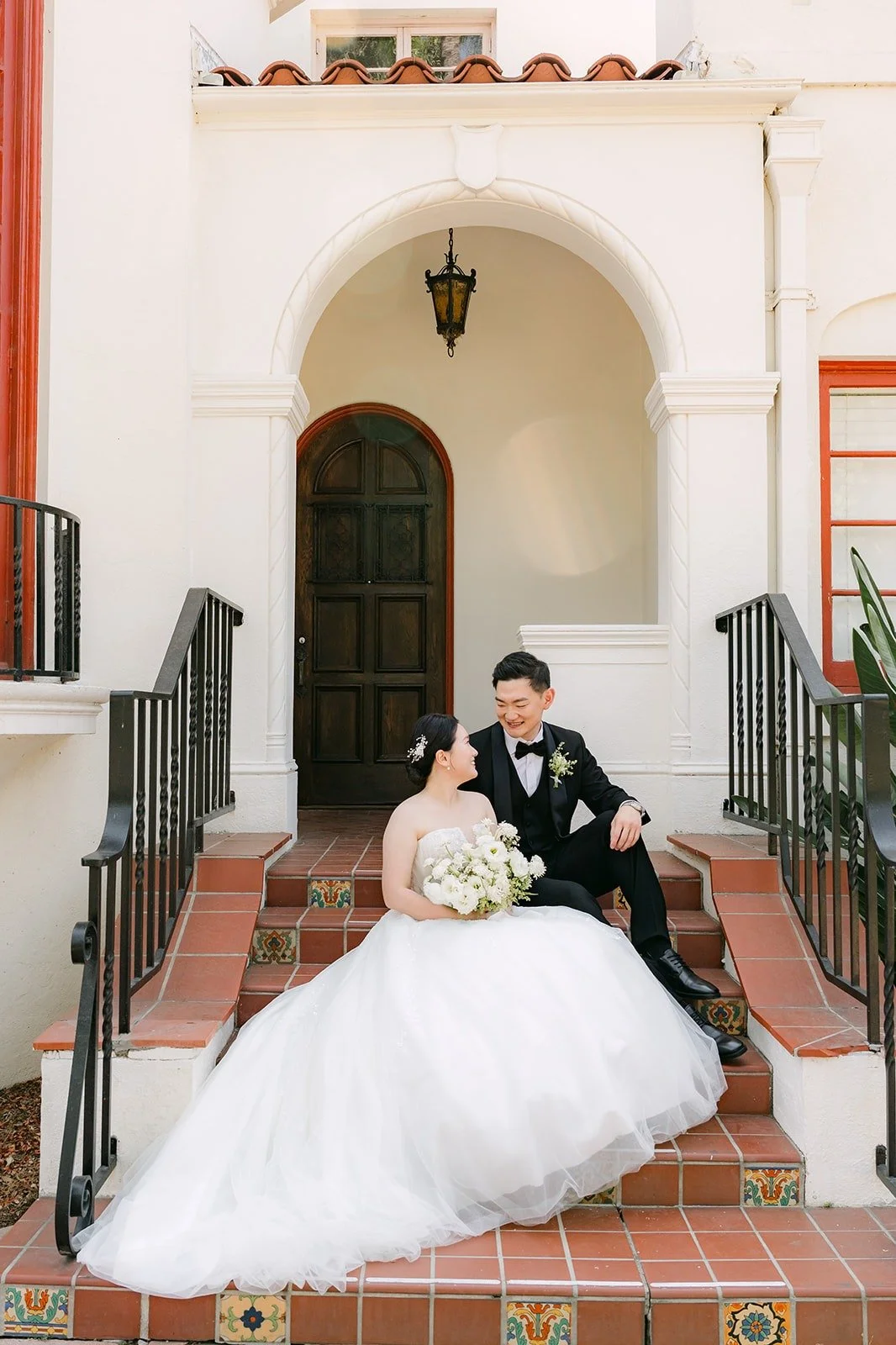 Amy and Sam sitting on the brick steps under the arched doorway