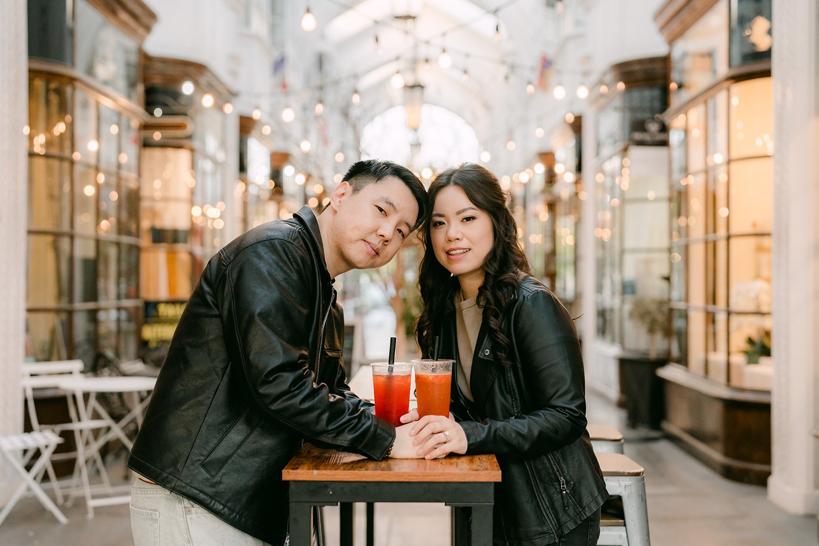Emily and James laugh together at a café table in the Burlington Arcade.